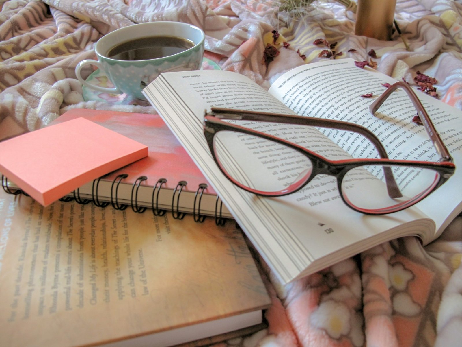 Cuaderno abierto con gafas de lectura y papelería sobre fondo claro