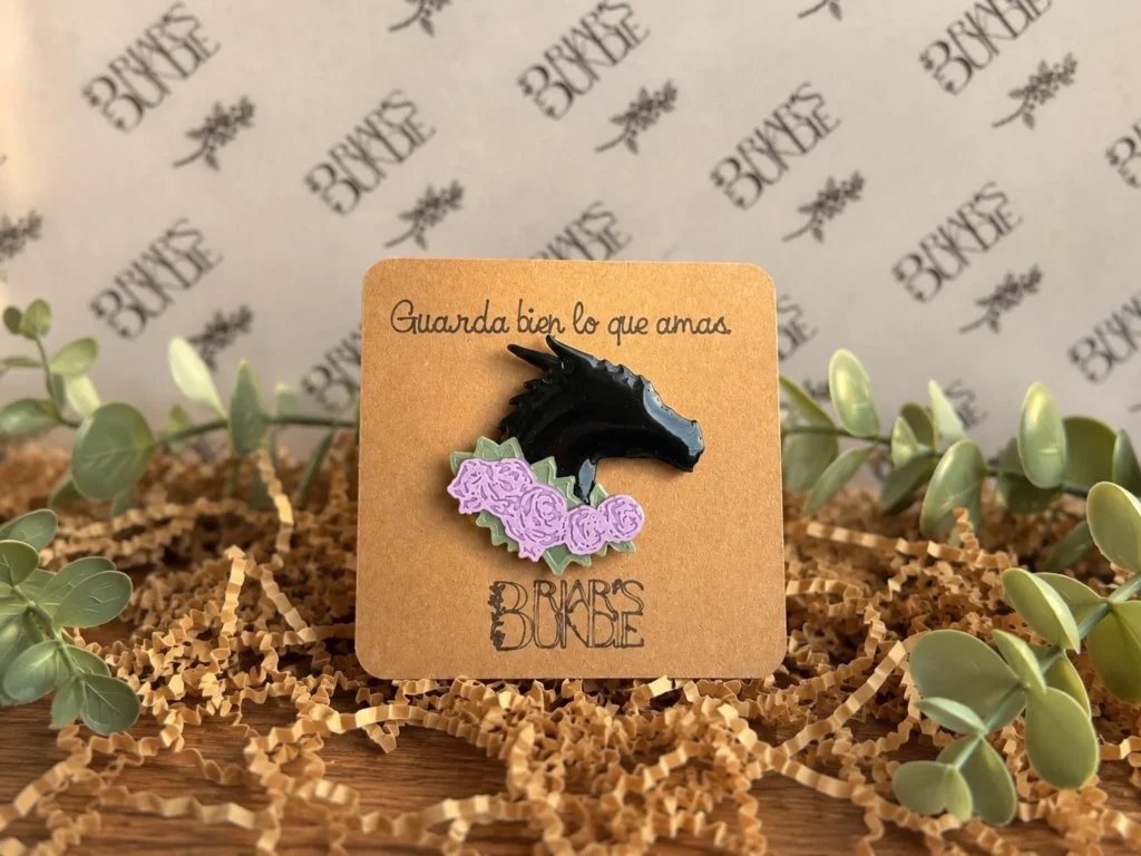 Broche de guiverno negro con flores lilas sobre su tarjeta de Briar's Bundle